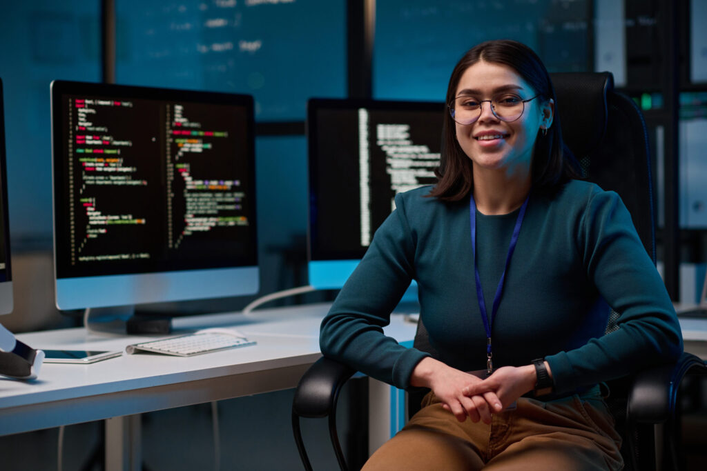 Woman sitting in front of computer monitors displaying code, representing cloud consulting and IT solutions for small businesses in Austin.